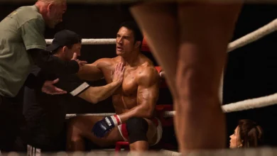 Cena do filme Coração de Lutador (2025), com Dwayne Johnson como Mark Kerr, recebendo orientações de sua equipe durante uma luta de MMA