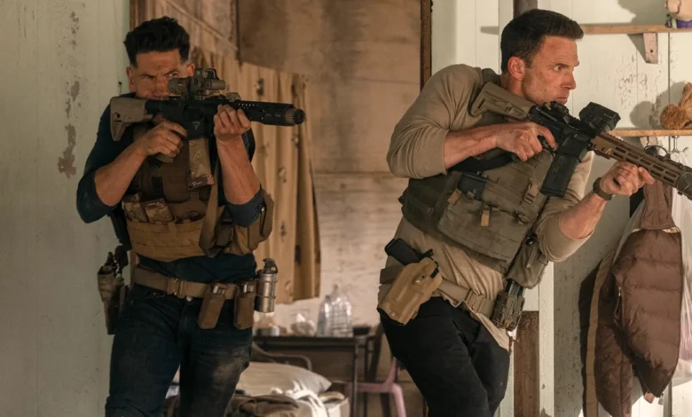 Cena de ação do filme O Contador 2, com dois homens armados e usando coletes táticos em um ambiente fechado, representando clima tenso e operação militar. Estreia nos cinemas em 24 de abril de 2025.