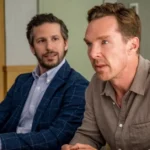 Cena do filme Os Roses: Até Que a Morte Os Separe (2025), com Benedict Cumberbatch e Andy Samberg em uma reunião tensa e decisiva.