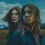 Julianne Moore e Sydney Sweeney em um campo aberto, com uma casa ao fundo e céu nublado, em cena do filme Echo Valley (2025).
