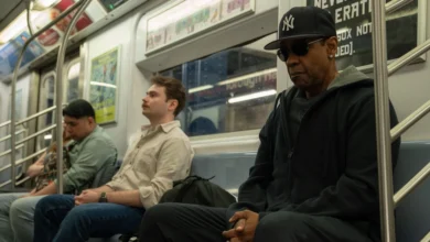 Cena do filme "Highest 2 Lowest" (2025), dirigido por Spike Lee, com Denzel Washington sentado em um metrô de Nova York, usando boné dos Yankees e óculos escuros, em clima tenso e introspectivo.