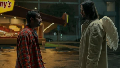 Keanu Reeves com asas de anjo contracena com Aziz Ansari em cena noturna do filme Quando o Céu se Engana (2025)