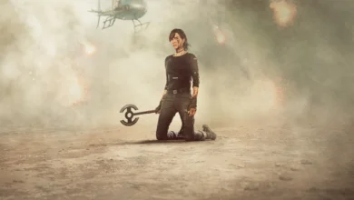 Charlize Theron ajoelhada como Andy, coberta de sangue e sujeira, segura seu machado em meio à fumaça e explosões na sequência de The Old Guard