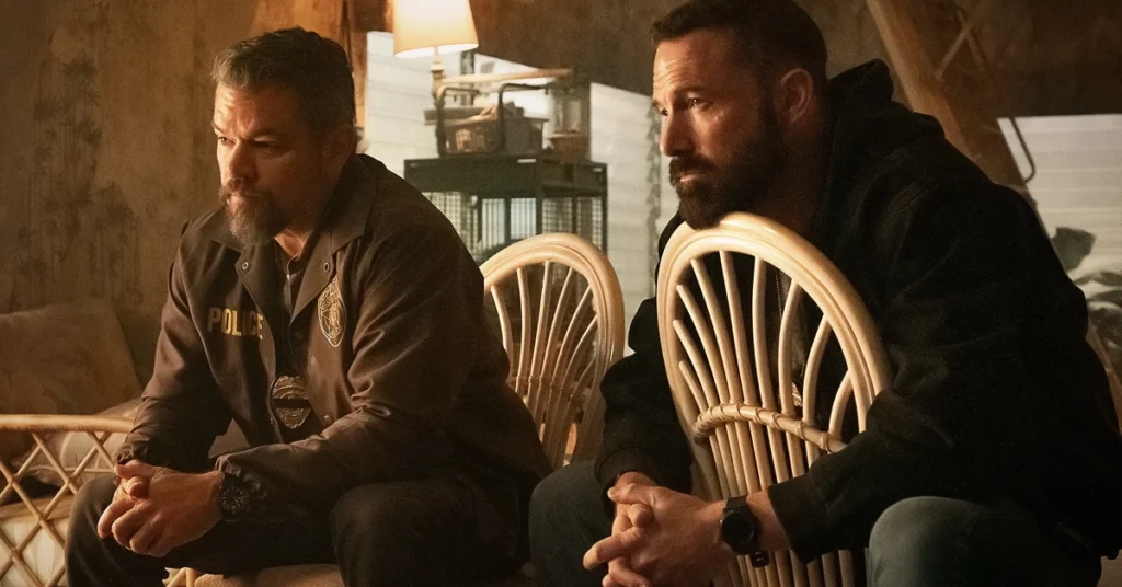 Cena do filme Dinheiro Suspeito (The Rip) com Matt Damon e Ben Affleck sentados e pensativos em um ambiente fechado