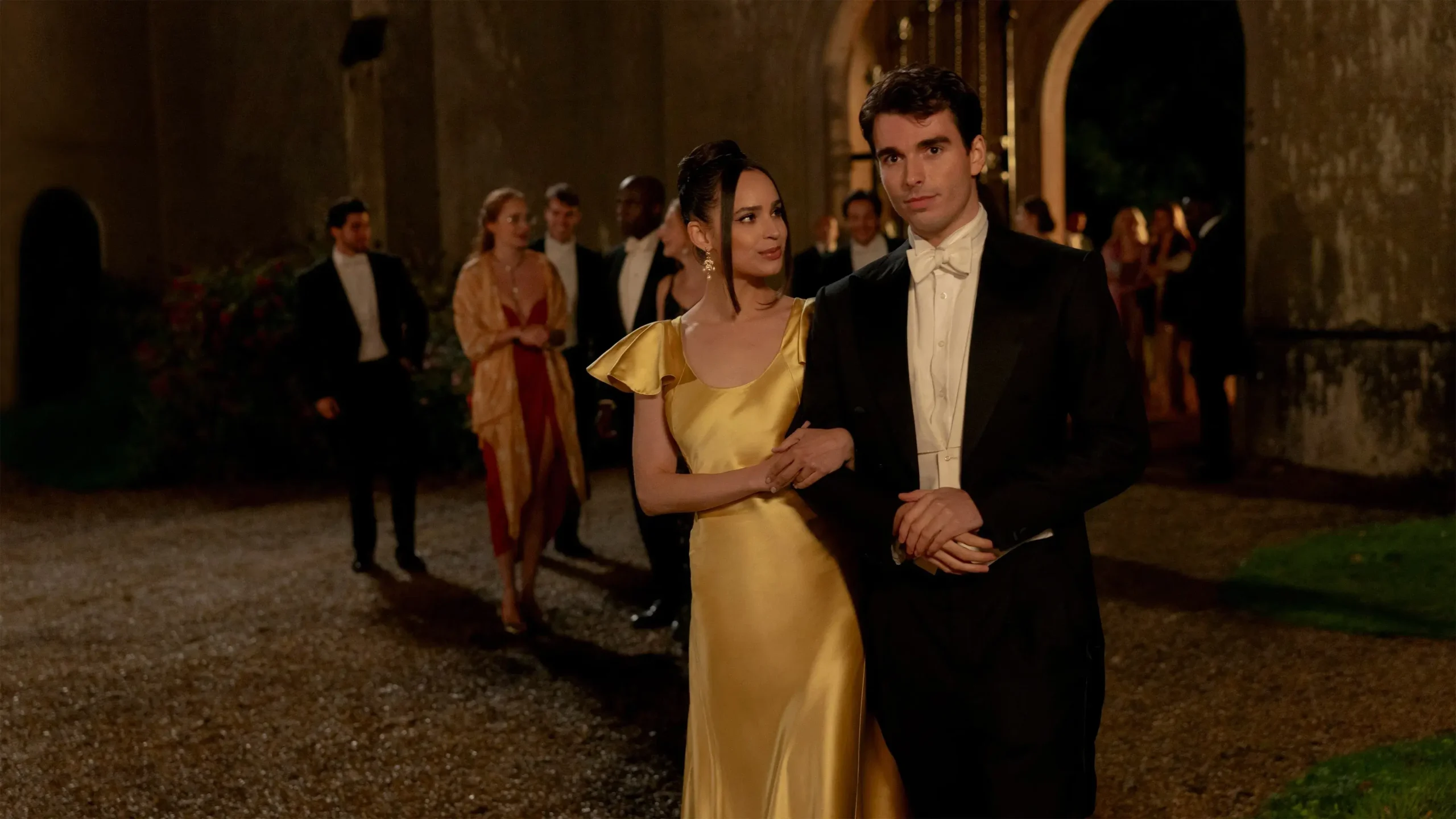 Sofia Carson e Corey Mylchreest elegantemente vestidos, de braços dados, durante um baile noturno em Meu Ano em Oxford (2025)