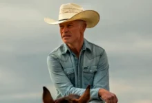 Neal McDonough como Joe Wainwright usando chapéu de cowboy e camisa jeans azul em cena do filme O Último Rodeio