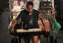 Shirley Cruz como a protagonista puxando um carrinho de recicláveis em cena do filme A Melhor Mãe do Mundo (2025)