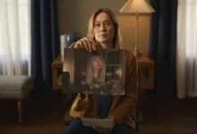 Camille Sullivan segura uma foto de Sarah Durn em cena do filme Terror em Shelby Oaks (2024), ambientado em uma sala iluminada por luz suave.