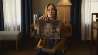 Camille Sullivan segura uma foto de Sarah Durn em cena do filme Terror em Shelby Oaks (2024), ambientado em uma sala iluminada por luz suave.