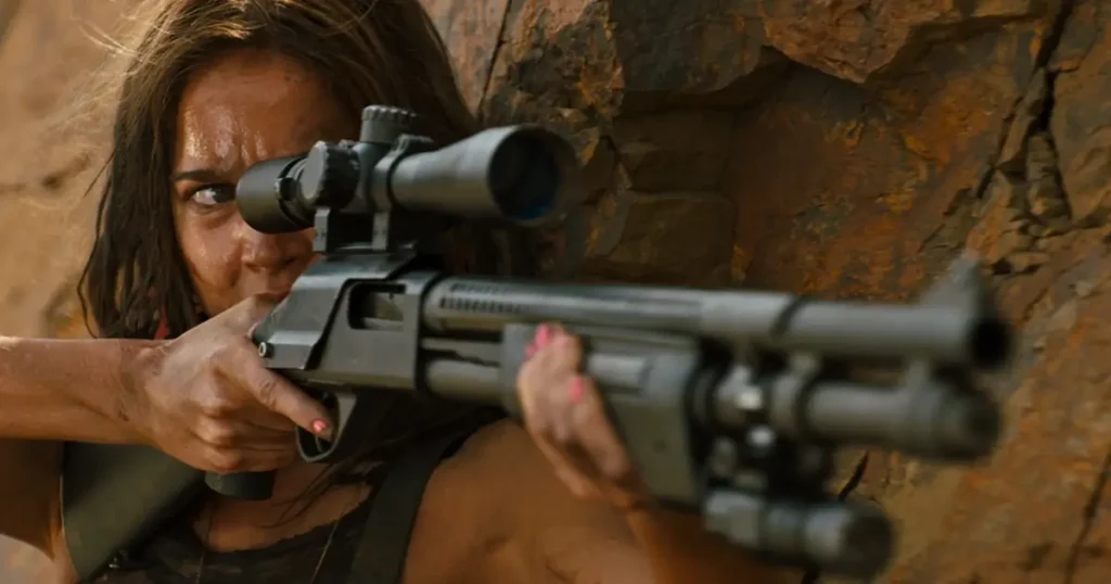 Matilda Lutz como Jen empunhando uma espingarda de precisão no filme Vingança (2017), dirigido por Coralie Fargeat.