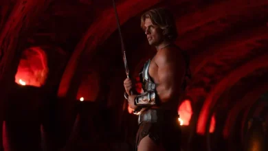 Nicholas Galitzine como He-Man em cena de Mestres do Universo (2026) com espada em ambiente iluminado por luz vermelha