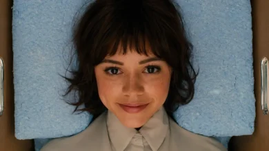 Jenna Ortega como Klara em cena do filme de ficção científica Klara e o Sol (2026), dirigida por Taika Waititi, deitada em uma superfície azul e olhando diretamente para a câmera.