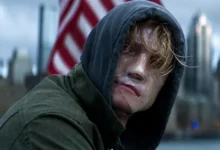Tom Rhys Harries como Matt Hagen, o Cara-de-Barro (Clayface), em cena do trailer de Cara-de-Barro (2026), usando um moletom com capuz enquanto observa o horizonte.