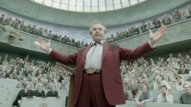 Tom Cruise em cena do Trailer de Digger, filme dirigido por Alejandro G. Iñárritu, durante um discurso em um grande tribunal cercado por uma multidão de espectadores.