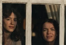 Esmé Creed-Miles e Daisy Edgar-Jones observam pela janela em uma cena de Razão e Sensibilidade (2026), nova adaptação cinematográfica do clássico de Jane Austen.