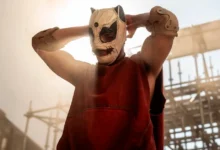 Personagem mascarado em cena de Corrida dos Bichos (2026), thriller de ação dirigido por Fernando Meirelles, em ambiente industrial tomado por fumaça.