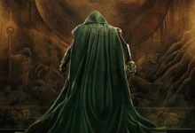 Robert Downey Jr. como Victor von Doom (Doctor Doom) diante de um enorme portal em Vingadores: Doutor Destino (2026), usando sua capa verde e segurando a máscara do vilão.