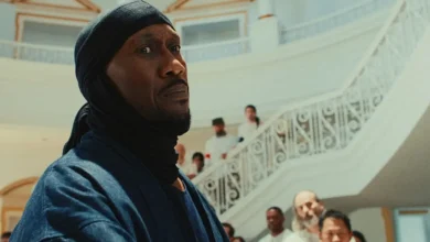 Mahershala Ali em cena de Your Mother Your Mother Your Mother (2026), em um salão com escadaria ao fundo durante momento de tensão no filme.