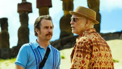 John Malkovich e Sam Rockwell contracenam em cena do filme Cavalo Selvagem Nove (2026), em uma paisagem com as estátuas moai da Ilha de Páscoa.