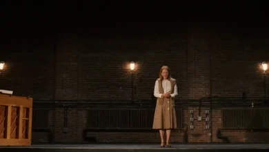 Julianne Moore em cena do filme A Grande Estreia (2026), em pé sobre um palco com paredes de tijolos e iluminação intimista.