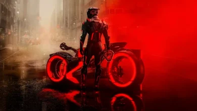 Personagem de Tron: Ares em traje futurista ao lado de moto iluminada em vermelho nas ruas de uma cidade sombria