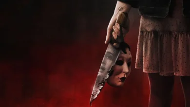 Pessoa segura uma faca ensanguentada com uma máscara refletida na lâmina em imagem promocional do filme Os Estranhos: Capítulo 2 (The Strangers: Chapter 2)