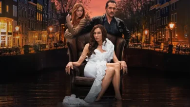 Famke Janssen sentada em uma poltrona, ao lado de Jacob Derwig e Elise Schaap, em cena promocional da série Império de Amsterdã (2025).