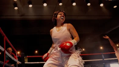 Sydney Sweeney como Christy Martin no ringue de boxe usando luvas vermelhas e roupa branca no filme Christy