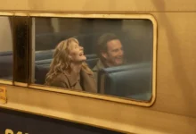Bradley Cooper e Laura Dern sentados em um vagão de trem em cena de “Isso Ainda Está de Pé?” (Is This Thing On?)