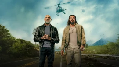 Jason Momoa e Dave Bautista em cena promocional do filme Dupla Perigosa (2026), com helicópteros ao fundo em ambiente tropical.