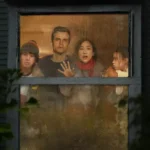 Wagner Moura, Greta Lee, Noah Alexander Sosnowski e Riley Chung observam o exterior através de uma janela em cena do filme A Última Casa (2026).