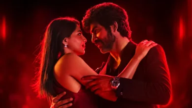 Arjun Das e Aishwarya Lekshmi em cena romântica do filme Amor (2026), sob iluminação vermelha intensa.