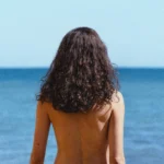 Margaret Qualley em O Amor de Sua Vida (2026), de costas diante do mar