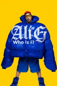 Pôster de Ali G: Who Iz I? (2026 Pôster de Ali G: Who Iz I? (2026), com Sacha Baron Cohen caracterizado como Ali G, usando jaqueta azul oversized com o título do filme estampado, óculos amarelos e gorro vermelho, sobre fundo amarelo.