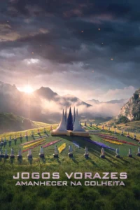 Pôster de Jogos Vorazes: Amanhecer na Colheita (2026), com tributos posicionados em um campo florido diante de uma estrutura central, cercada por montanhas e iluminada pelo nascer do sol.