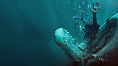 Austin Abrams como o mergulhador em Dentro da Baleia (2026), diante de uma criatura marinha gigante nas profundezas do oceano.