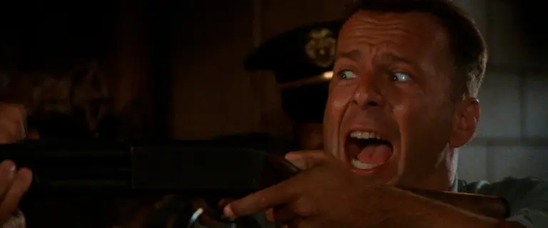 Bruce Willis gritando e empunhando uma arma em cena do filme O Jogador (1992)