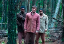 Três homens, Jorge Guerreiro, Pierre Baitelli e George Sauma, em meio a uma floresta densa e escura, em cena do filme de terror brasileiro A Própria Carne, produção Jovem Nerd.