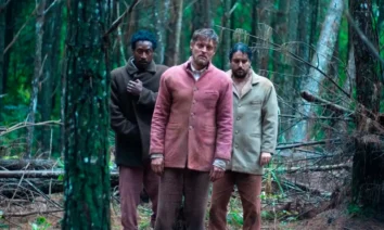Três homens, Jorge Guerreiro, Pierre Baitelli e George Sauma, em meio a uma floresta densa e escura, em cena do filme de terror brasileiro A Própria Carne, produção Jovem Nerd.