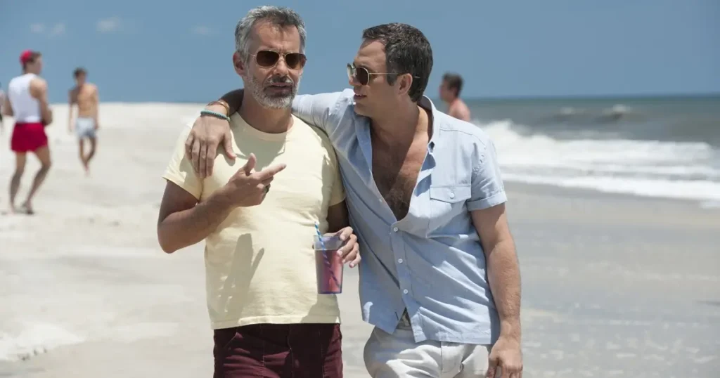 Dois personagens caminhando abraçados na praia em uma cena de The Normal Heart (2014), filme marcante sobre os primeiros anos da crise da AIDS.
