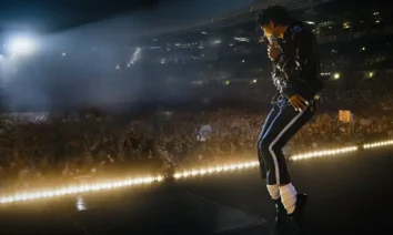 Jaafar Jackson caracterizado como Michael Jackson em cena do filme Michael, dançando em palco iluminado diante de multidão em estádio lotado