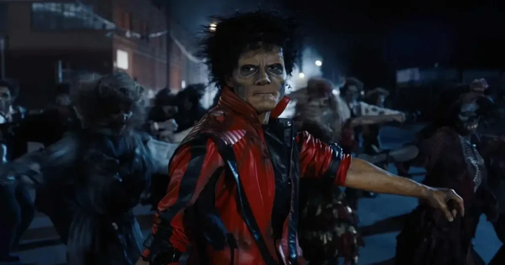 michael thriller Jaafar Jackson caracterizado como Michael Jackson na icônica cena de Thriller, usando jaqueta vermelha e maquiagem de zumbi cercado por dançarinos