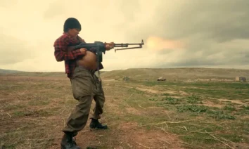 Teyana Taylor como Perfidia disparando uma metralhadora em campo aberto no filme Uma Batalha Após A Outra (2025)