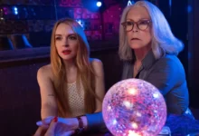 Jamie Lee Curtis e Lindsay Lohan em cena iluminada por luzes coloridas e uma bola de cristal no filme Uma Sexta-Feira Mais Louca Ainda (2025).