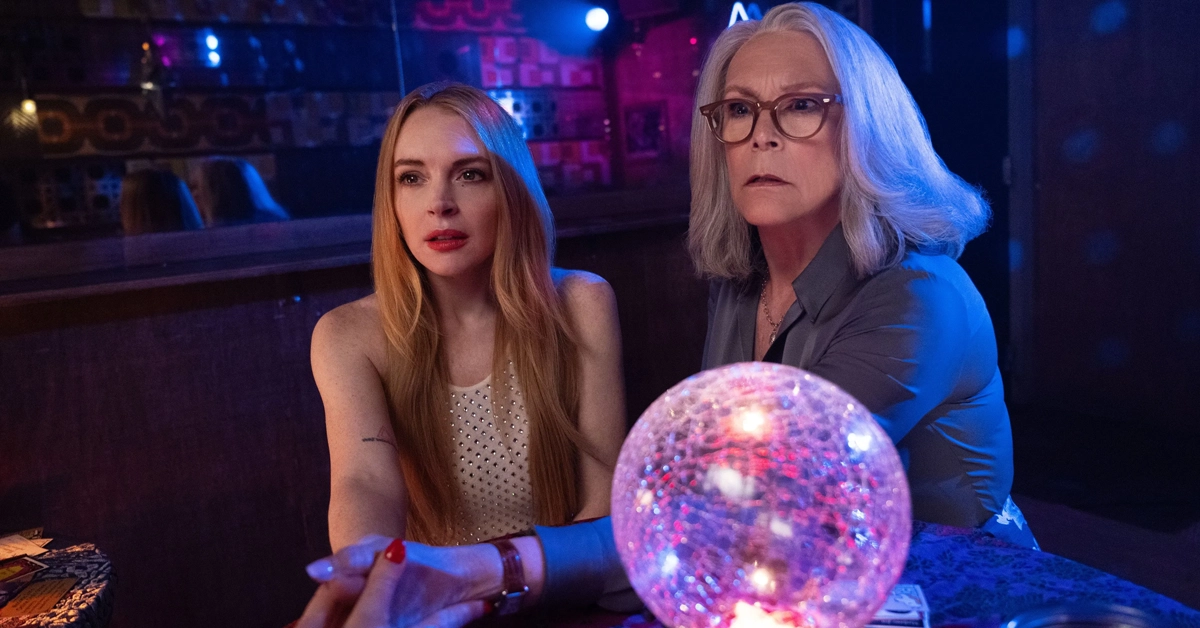 Jamie Lee Curtis e Lindsay Lohan em cena iluminada por luzes coloridas e uma bola de cristal no filme Uma Sexta-Feira Mais Louca Ainda (2025).