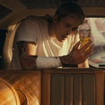Cena do filme Confinado, um dos novos filmes claustrofóbicos, mostra o personagem de Bill Skarsgård dentro de um carro apertado e fechado, ferido e segurando uma garrafa com líquido amarelo, transmitindo tensão e isolamento.