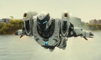 Armadura de alta tecnologia voadora usada por Riri Williams na série Coração de Ferro, da Marvel Studios, sobrevoando um rio em ambiente urbano.