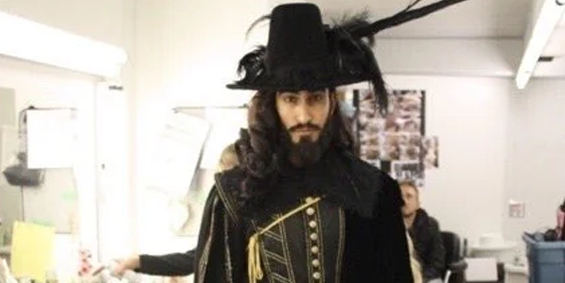 daniel malik black phillip O ator Daniel Malik caracterizado como a forma humana de Black Phillip nos bastidores do filme A Bruxa (2015), com figurino sombrio e chapéu com penas, representando a encarnação do mal