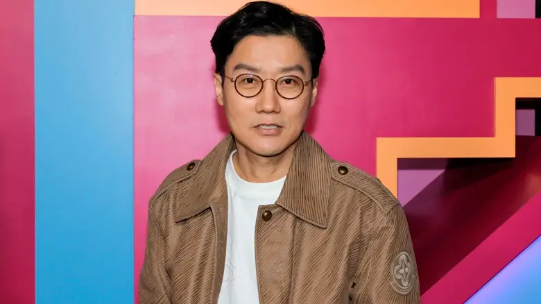 hwang dong hyuk round 6 O diretor e criador de Round 6, Hwang Dong-hyuk, posa em frente a um fundo colorido durante evento promocional