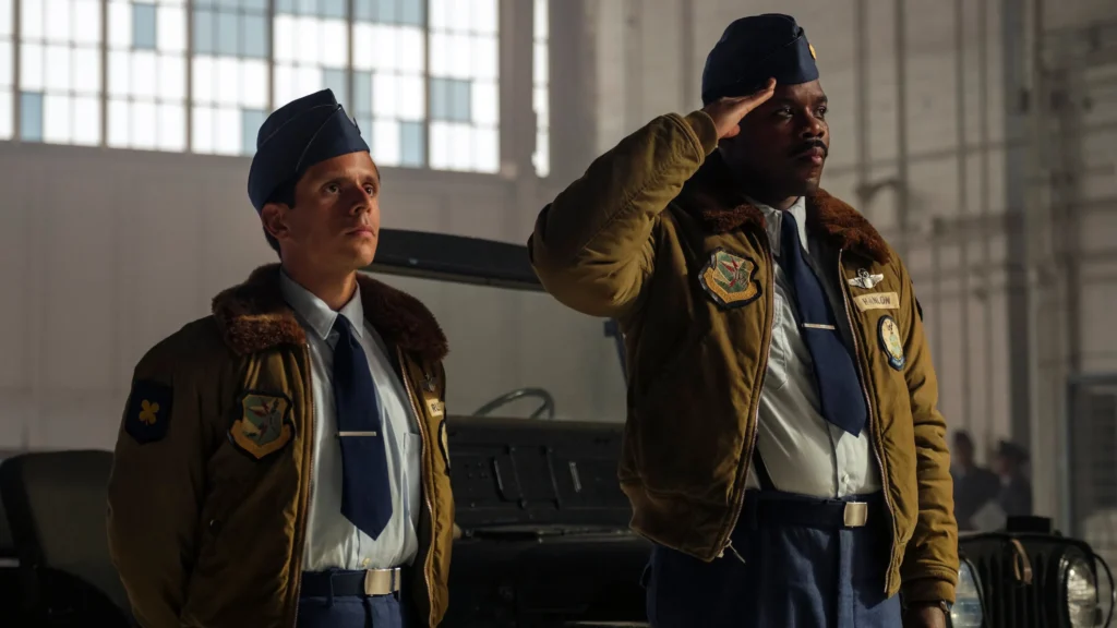 atores Ricky Gray e Jovan Adepo Cena da série It: Bem-Vindo a Derry (2025), com os atores Ricky Gray e Jovan Adepo usando uniformes militares em um hangar, em uma atmosfera de tensão e seriedade